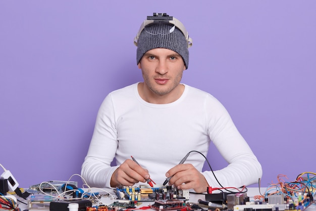 Free photo caucasian young man dresss white shiert and gray cap, digital electronic engineer repairing computer motherboard in workshop