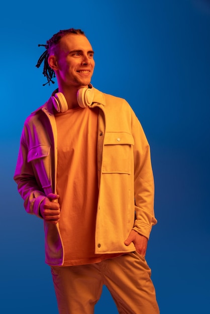 Caucasian young man in headphones isolated on blue studio background in neon Concept of human emotions facial expression