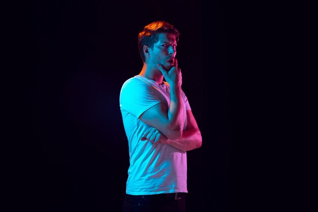 Caucasian young man portrait on dark in neon