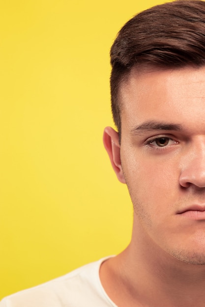 Caucasian young man's close up portrait on yellow background