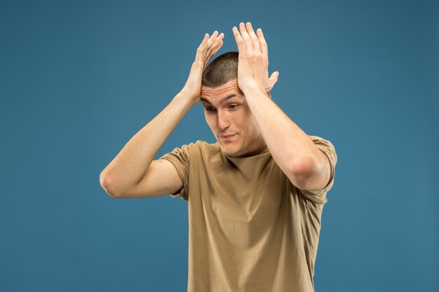 Caucasian young man's half-length portrait on blue  space. Beautiful male model in shirt