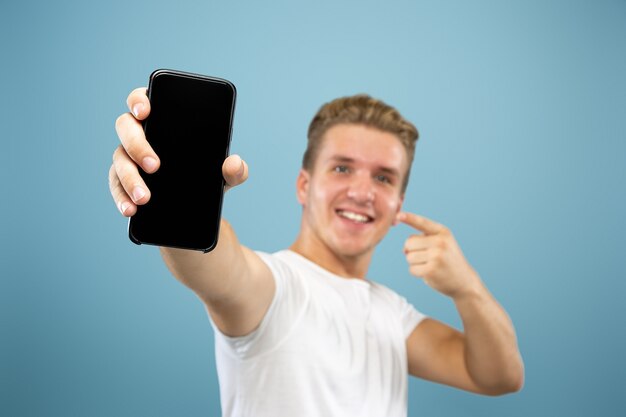 Caucasian young man's half-length portrait on blue studio