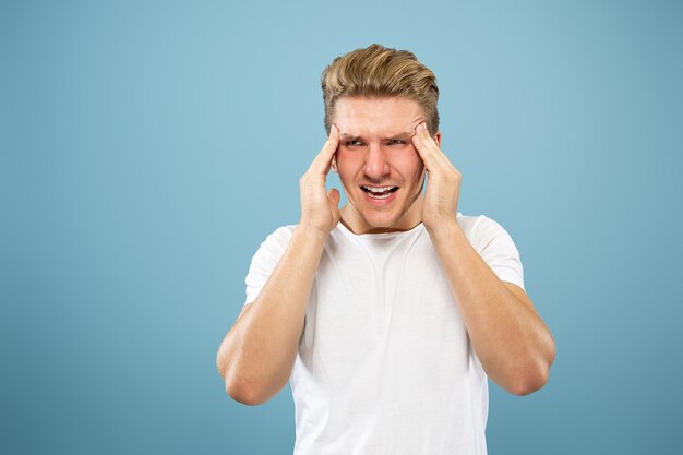 Caucasian young man's half-length portrait on blue studio