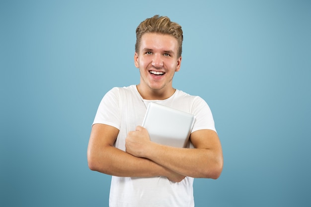 Caucasian young man's half-length portrait on blue studio