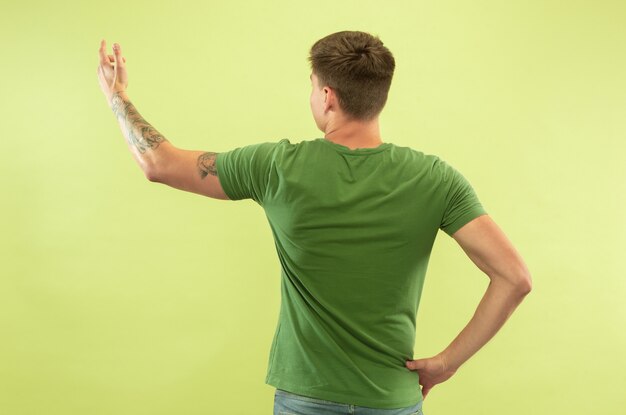 녹색 공간에 백인 젊은 남자의 절반 길이 초상화. 셔츠에 아름 다운 남성 모델