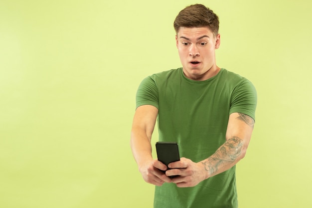 Caucasian young man's half-length portrait on green  space. Beautiful male model in shirt