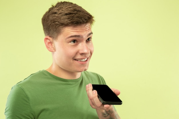 Caucasian young man's half-length portrait on green  space. Beautiful male model in shirt