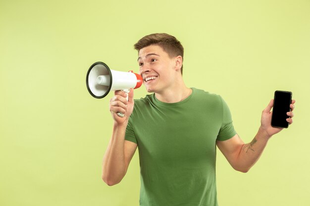 Caucasian young man's half-length portrait on green studio space. Beautiful male model in shirt