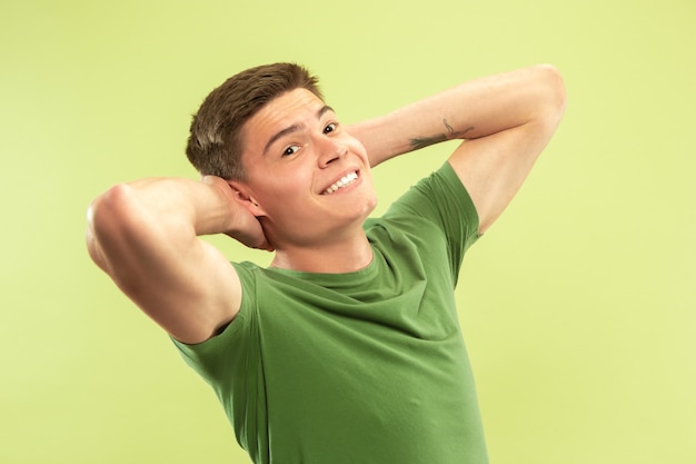 Caucasian young man's half-length portrait on green studio