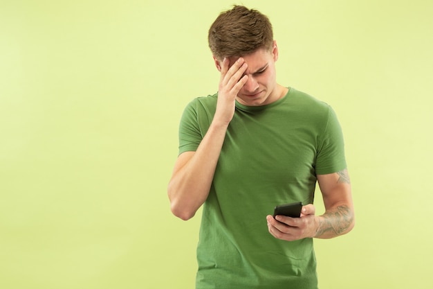 Caucasian young man's half-length portrait on green studio