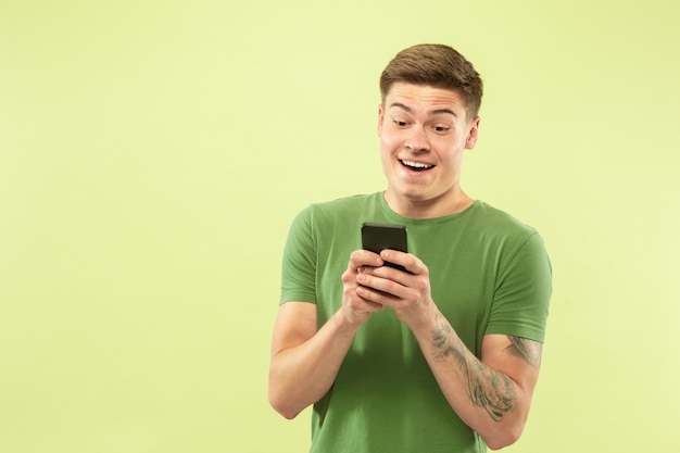 Caucasian young man's half-length portrait on green studio