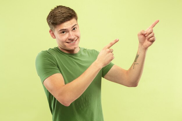 Caucasian young man's half-length portrait on green studio