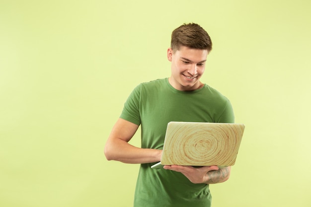 Бесплатное фото Поясной портрет кавказского молодого человека на зеленом пространстве студии. красивая мужская модель в рубашке