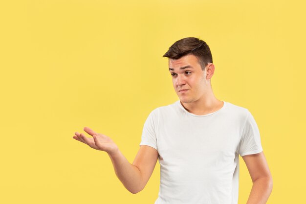 Caucasian young man's half-length portrait on yellow studio