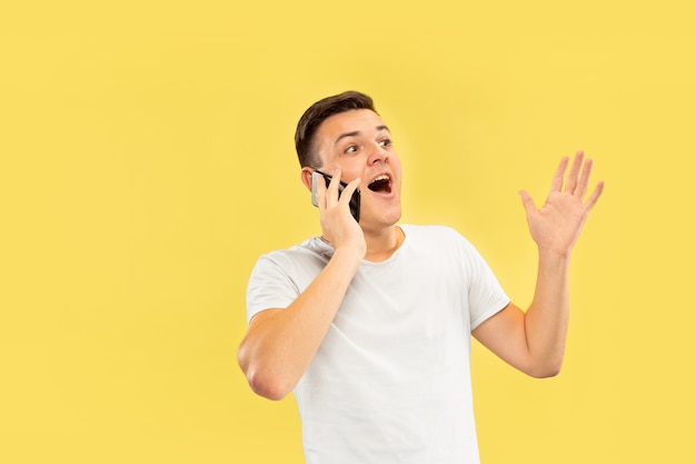 Caucasian young man's half-length portrait on yellow studio