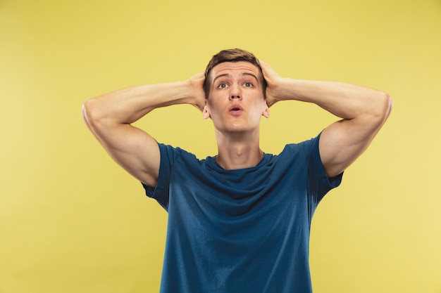 Caucasian young man's half-length portrait on yellow studio