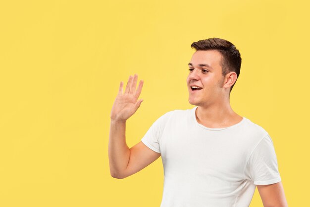 Caucasian young man's half-length portrait on yellow studio