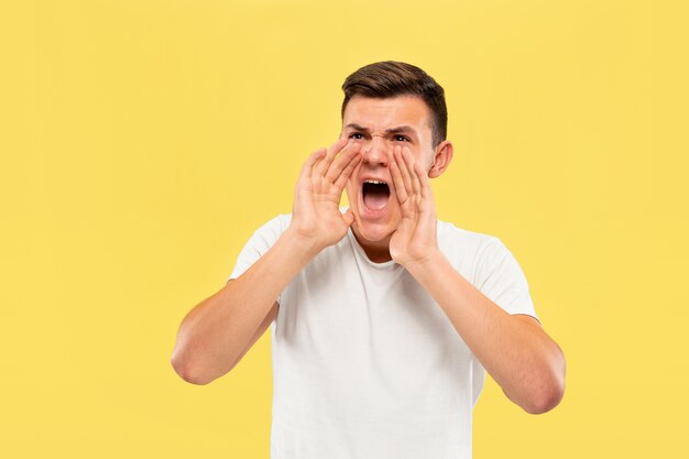 Caucasian young man's half-length portrait on yellow studio