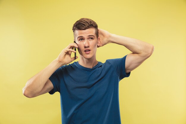 Caucasian young man's half-length portrait on yellow studio