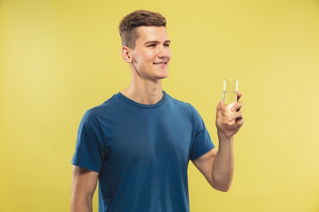 Caucasian young man's half-length portrait on yellow studio