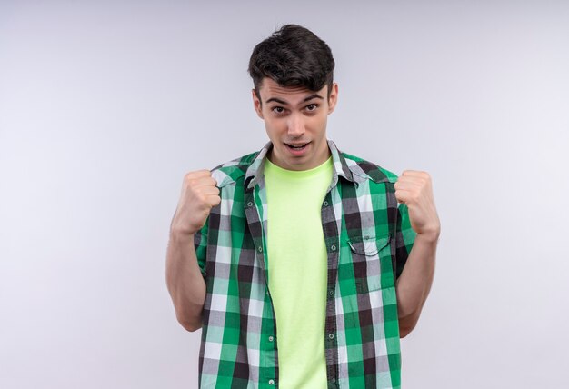 caucasian young man wearing green shirt doing strong gesture on isolated white wall