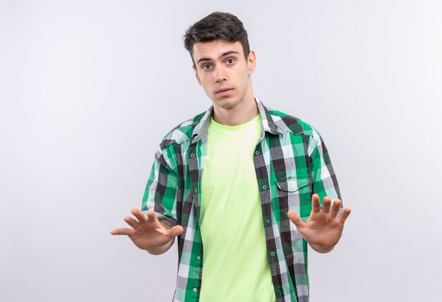 caucasian young man wearing green shirt showing stop gesture on isolated white wall
