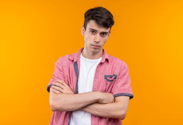 caucasian young man wearing pink shirt crossing hands on isolated orange wall