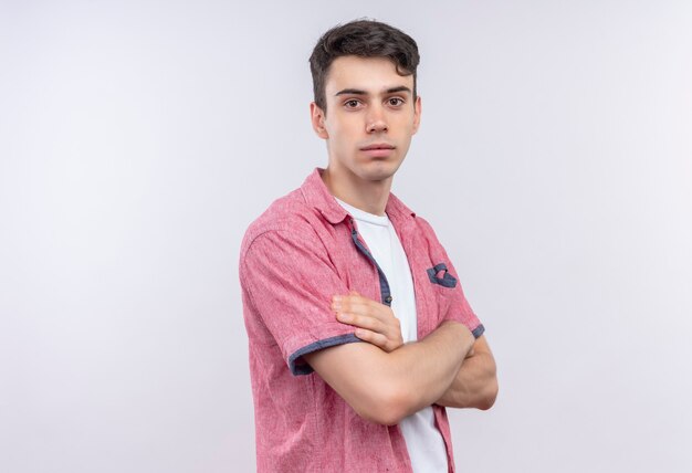 caucasian young man wearing pink shirt crossing hands on isolated white wall