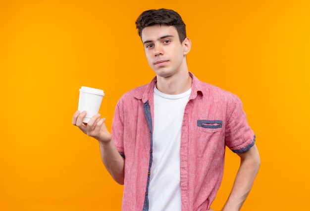 격리 된 오렌지 벽에 커피 한잔 들고 분홍색 셔츠를 입고 백인 젊은 남자