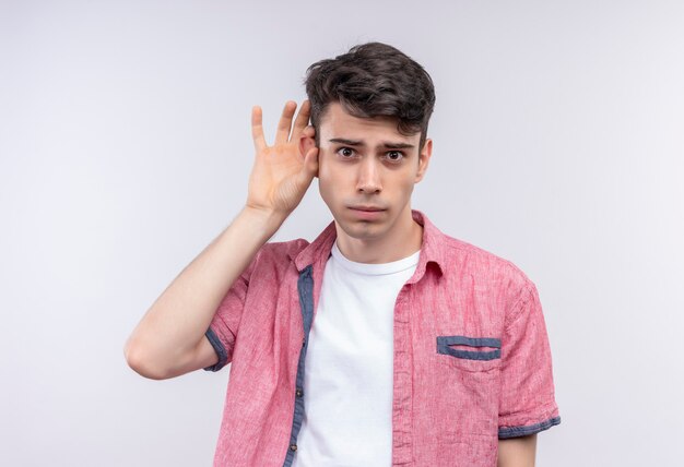 caucasian young man wearing pink shirt showing listen gesture on isolated white wall