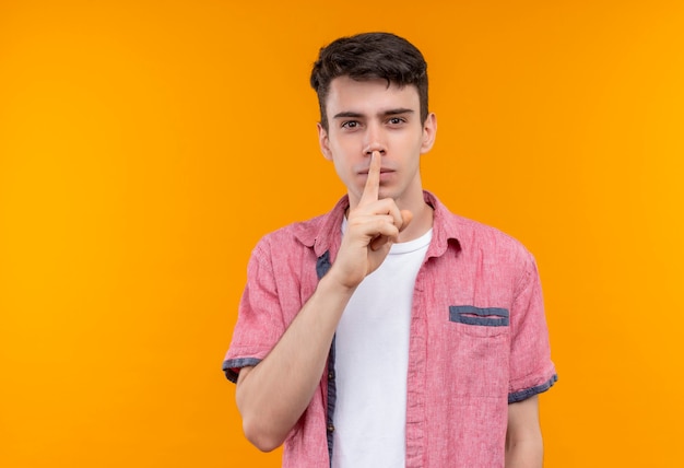 caucasian young man wearing pink shirt showing silence gesture on isolated orange wall
