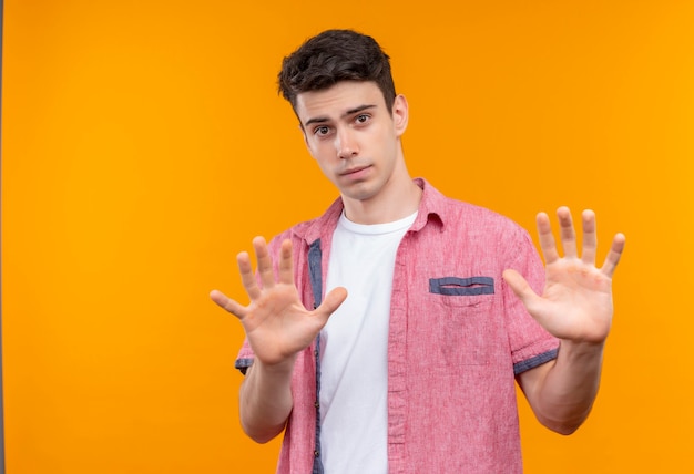 caucasian young man wearing pink shirt showing stop gesture on isolated orange wall