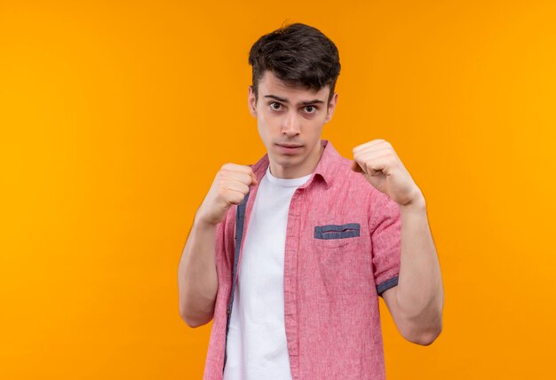 caucasian young man wearing pink shirt standing in fighting pose on isolated orange wall