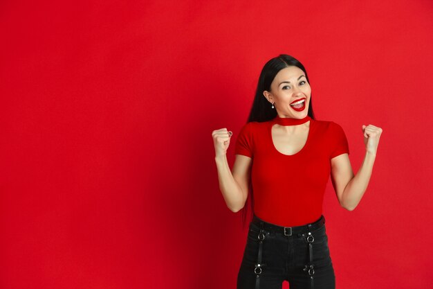 Caucasian young woman monochrome portrait on red  wall emotional and expressive