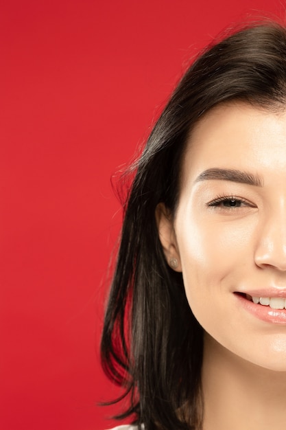 Caucasian young woman's close up portrait on red studio