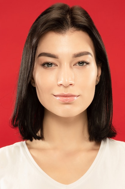 Caucasian young woman's close up portrait on red wall