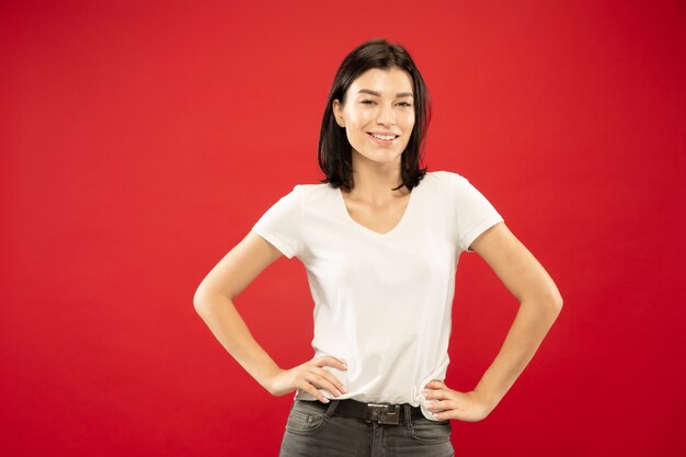 Caucasian young woman's half-length portrait on red studio