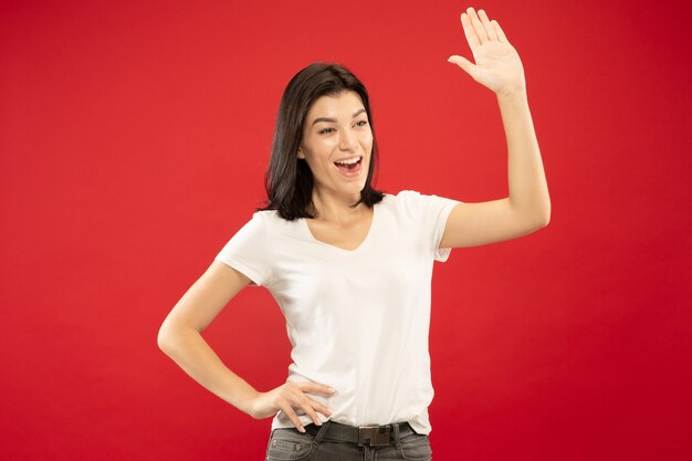 Caucasian young woman's half-length portrait on red studio