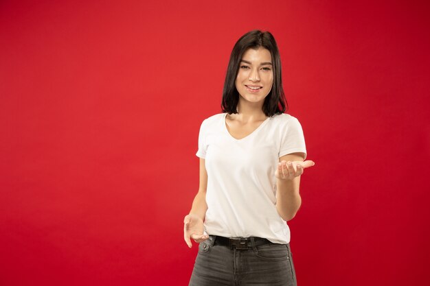 Caucasian young woman's half-length portrait on red studio