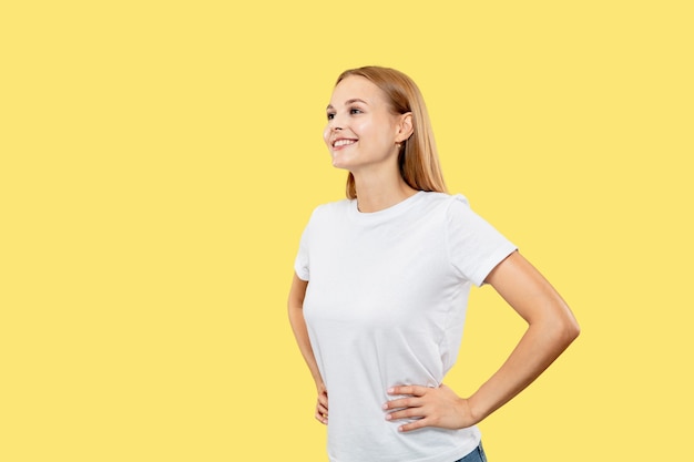 노란색 스튜디오 배경에 백인 젊은 여자의 절반 길이 초상화. 흰 셔츠에 아름다운 여성 모델