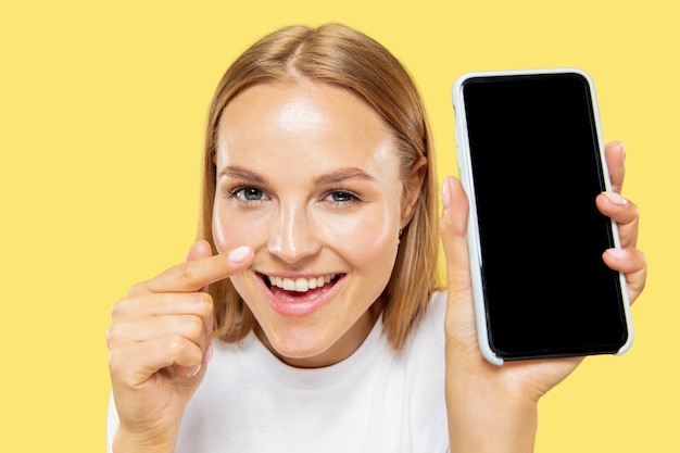 Free photo caucasian young woman's half-length portrait on yellow studio