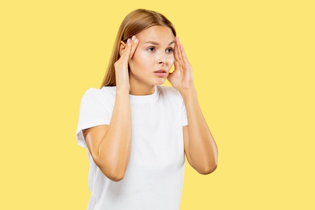 Caucasian young woman's half-length portrait on yellow studio