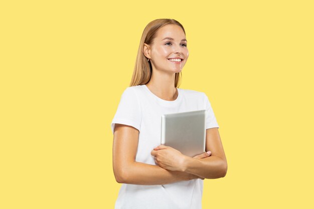 Caucasian young woman's half-length portrait on yellow studio