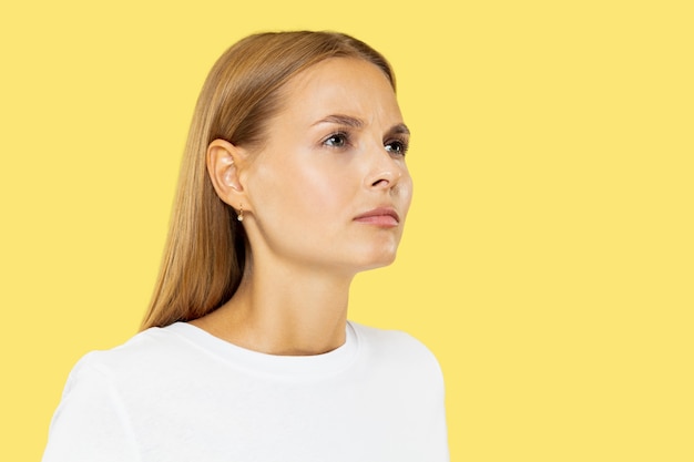 Caucasian young woman's half-length portrait on yellow studio