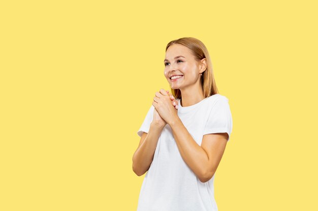 Caucasian young woman's half-length portrait on yellow studio