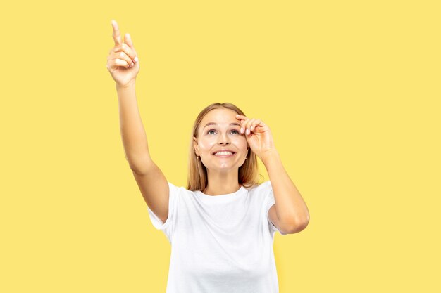 Caucasian young woman's half-length portrait on yellow studio