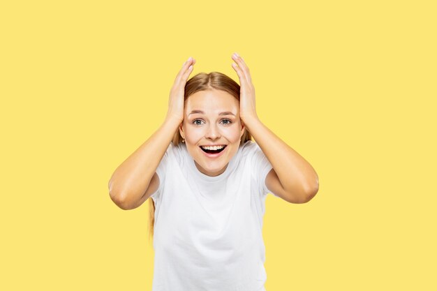 Caucasian young woman's half-length portrait on yellow studio