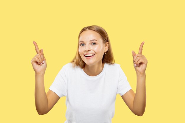 Caucasian young woman's half-length portrait on yellow studio