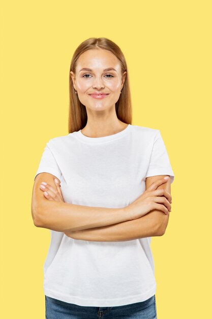 Caucasian young woman's half-length portrait on yellow studio