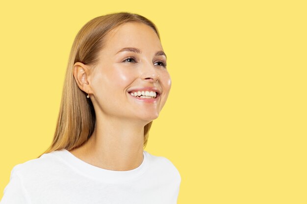 Caucasian young woman's half-length portrait on yellow studio